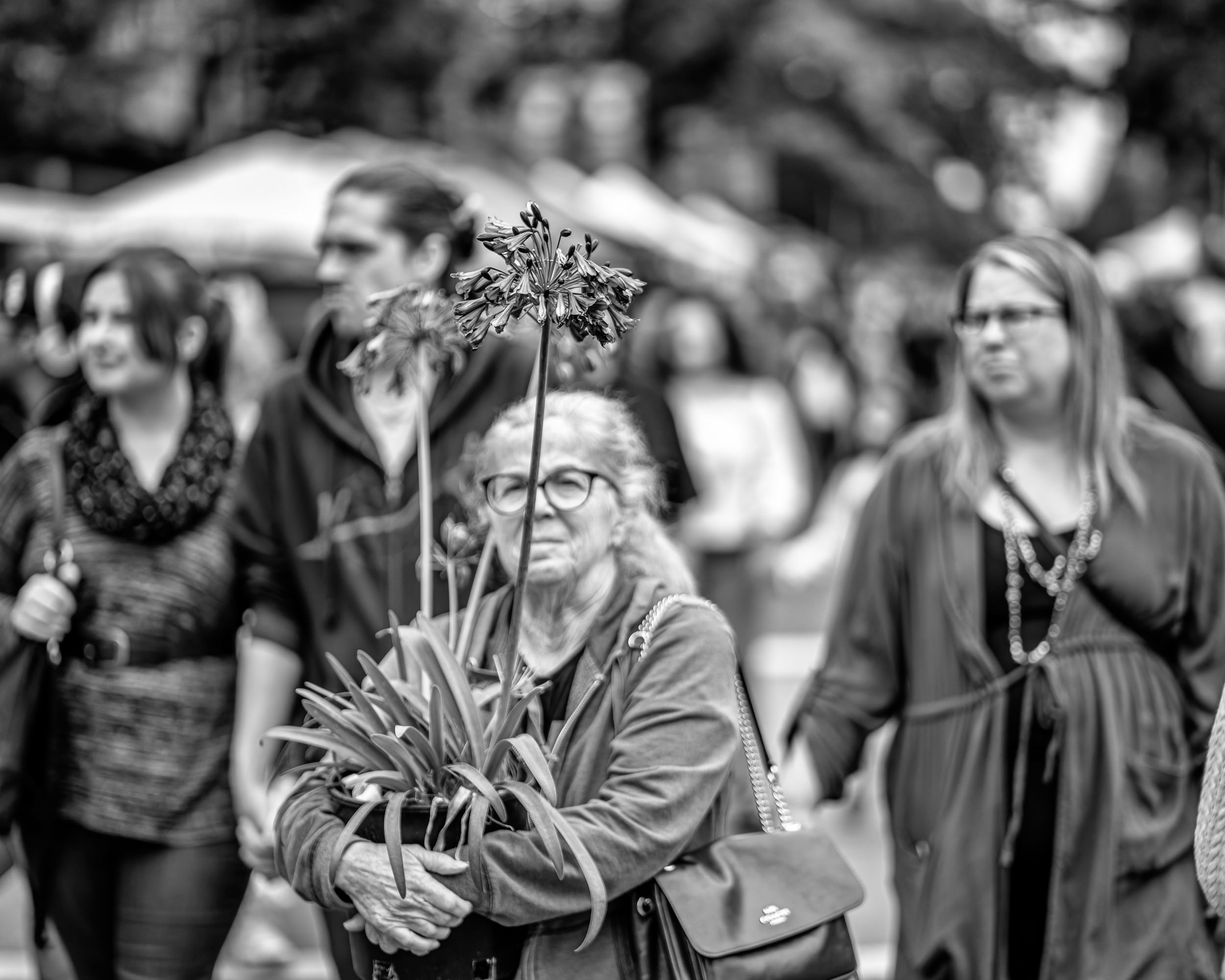 2026_09_19_Vancouver_85mm_0093-Edit-Edit_2500 ‣ In The Viewfinder Outdoor farmers market scene with stalls, shoppers, and a prominent banner reading'Welcome to the Market!' (Vancouver Farmers Market) in black and white.